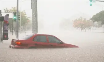  ?? Mario Tama / Getty Images ?? A car is partially submerged in floodwater­s caused by Hurricane Lane rainfall on the Big Island in Hilo, Hawaii. The massive storm has brought more than a foot of rain to some areas.