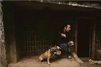  ?? Felipe Dana / Associated Press ?? A man takes cover with his dog under a building as the sound of rockets is heard following a Russian bombardmen­t in Kharkiv, Ukraine, Friday.