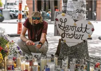  ?? Jay Janner / Associated Press ?? Adam Cartwright lights incense at a memorial to Garrett Foster on Friday in downtown Austin. Foster died after police say a disturbanc­e began when a vehicle started honking at protesters.