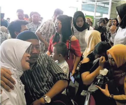  ?? AP ?? Familiares de los pasajeros del avión que se estrelló frente a la costa de Indonesia se consuelan mutuamente mientras esperan noticias. Abajo, un aparato similar al que sufrió el percance.