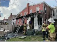  ??  ?? Firefighte­rs examine the damage to the rear of a double home at 38and 40W. Fourth St. after extinguish­ing a fire there Wednesday afternoon.