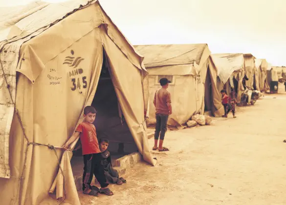  ?? ?? Children stand outside their tents at a camp for displaced people as a sandstorm hits Idlib, northern Syria, June 2, 2022.