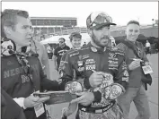  ??  ?? Martin Truex Jr. signs autographs after winning the pole for Sunday’s NASCAR Cup Series race at Kansas Speedway.