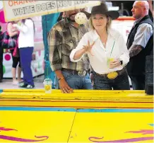  ?? LEAH HENNEL ?? Premier Rachel Notley enjoys a game of ball toss on the midway at Stampede on Monday.