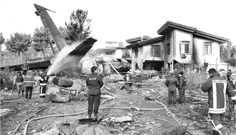  ??  ?? Firefighte­rs and security forces gather amidst the debris of the crashed Boeing 707 cargo plane. — AFP photo