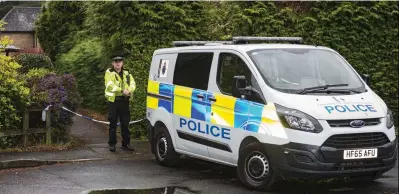  ??  ?? Leafy idyll: A police officer stands guard at the scene of the killing in St Ives, Dorset