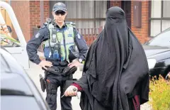  ?? AFP ?? Police stand guard as a woman leaves a house raided by police in the Melbourne suburb of Dallas yesterday.