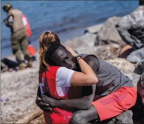  ?? (File Photo/AP/Bernat Armangue) ?? A migrant is comforted by a member of the Spanish Red Cross on May 18 at the Spanish enclave of Ceuta near the border of Morocco and Spain.