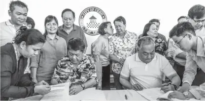 ?? THE FREEMAN FILE PHOTO ?? Cebu City Mayor Tomas Osmeña and Governor Hilario Davide III sign the deed of donation to seal the land swapping deal involving 93-1 lots few months ago. The City Council now wants an update on the mode of payment.