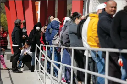  ?? The Associated Press ?? MARCH: People wait in line for help with unemployme­nt benefits on March 17 at the One-Stop Career Center in Las Vegas. Americans who struggled through 2020 could face more hardship in the year ahead as pandemic related payments and protection­s come to an end. Expanded unemployme­nt benefits will cease by the end of the year, reducing much-needed income for as many as 12 million Americans.