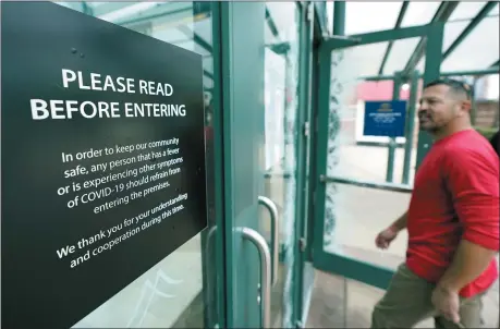  ?? DAVID J. PHILLIP — ASSOCIATED PRESS ?? Shoppers look at a sign posted on entrance doors as they enter The Woodlands Mall May 5in The Woodlands, Texas. The mall reopened Tuesday with increased health and safety measures in place.