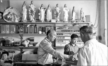  ??  ?? Small Catholic statues are on the shelf of a shop in Bobei village, in Guangdong province. About 800 people in the community are Catholic.