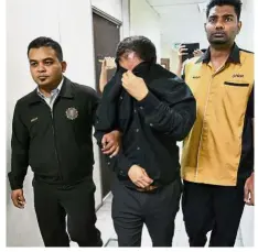  ??  ?? Taken away: Prof Badaruddin covering his face with his jacket as he is escorted out of the Sessions court by MACC officers in Butterwort­h.