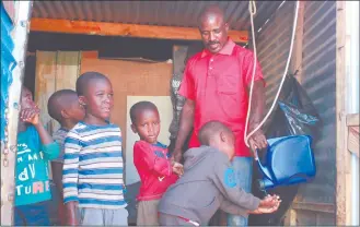  ?? Photo: Emmency Nuukala ?? Precaution… A father helps his children to sanitise their hands in the Kilimanjar­o informal settlement.