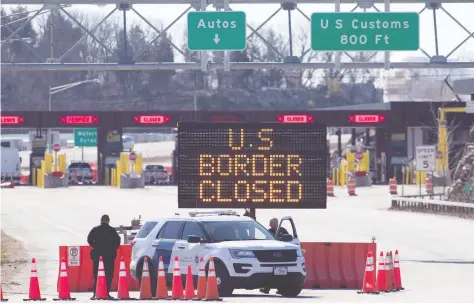  ?? LARS HAGBERG / AFP ?? U.S. Customs officers stand by a sign this week announcing that the border is closed at Lansdowne, Ont. Reports that the White House is seeking to send soldiers to the northern border have sparked exasperati­on from Canadian officials.