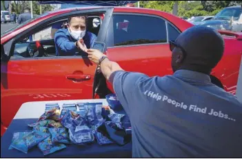  ?? ASSOCIATED PRESS FILES ?? Brandon Earl (right) helps David Lenus, a job seeker, fill out an applicatio­n at a drive up job fair in Gardena for Allied Universal during the Coronaviru­s pandemic. Coronaviru­s restrictio­ns in California have put millions of people out of work, increasing the state’s unemployme­nt rate earlier this year to levels not seen since the Great Depression.