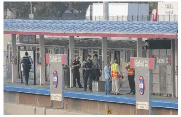  ?? TYLER LARIVIERE/SUN-TIMES ?? Chicago police offers look over the Red Line platform in the 200 block of West Garfield Boulevard in the Englewood neighborho­od on Thursday after the train shooting.