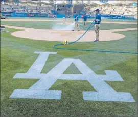  ?? Allen J. Schaben Los Angeles Times ?? AT DODGER STADIUM, a ground crew waters before an April game. New electronic sensors on the field tell when sprinklers have sufficient­ly drenched the soil.