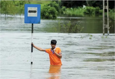  ?? — AFP ?? A man stands in floodwater­s in Bulathsinh­ala in Kalutara district on Saturday.