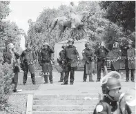  ?? STEVE HELBER, AP ?? State police in riot gear guard Lee Park in Charlottes­ville.