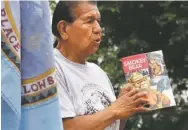  ?? RICK ROMANCITO/ TAOS NEWS ?? Paul Romero, one of the Taos Pueblo Snowballs who located the original Smokey Bear, holds up the comic book distribute­d to schoolchil­dren depicting what he said was the incomplete story during a July 2008 ceremony and acknowledg­ment by the Bureau of Indian Affairs of the Snowballs' historic role.