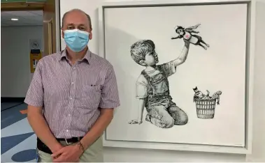  ??  ?? Dr Simon Wills standing by Banksy’s painting at Southampto­n General Hospital