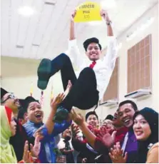  ?? BBXPIX ?? Students and teachers of SMKA Maahad Hamidiah in Kajang, Selangor, tossing Muhammad Afiq Ismail in the air after he scored a CGPA 3.75.