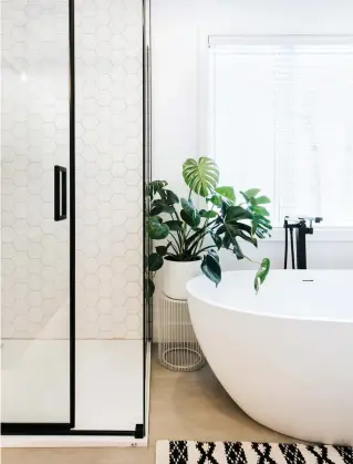  ??  ?? Présente dans la douche et sur le dosseret, la céramique hexagonale blanche apporte une belle texture aux murs.