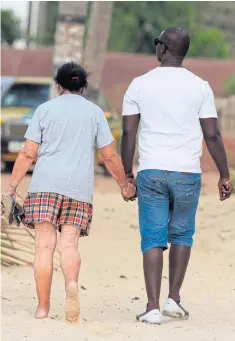  ??  ?? COMING TO GRIPS: The Gambia has long held a reputation as a sex tourism hotspot, particular­ly for older European women seeking young men. GETTING INTO THEIR STRIDE: A man walks past a woman on the beach of Kololi. The Gambia wants to market itself as an attractive nature and wildlife destinatio­n.