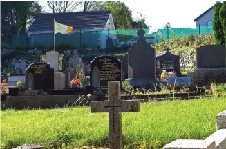  ??  ?? An Irish flag flies over the graves in a cemetery in Carrickcar­nan next to the Jonesborou­gh Parish located in Northern Ireland.