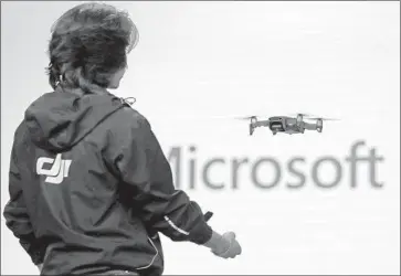  ?? Elaine Thompson Associated Press ?? A WORKER with tech firm DJI demonstrat­es a drone during the keynote at Build, Microsoft’s conference for software developers, in Seattle in 2018. Microsoft wants to make software to teach devices how to behave.