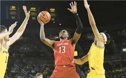  ?? JOSE JUAREZ/AP ?? Maryland guard Hakim Hart puts up a shot in between Michigan center Hunter Dickinson, left, and forward Terrance Williams II in the first half of Sunday’s game in Ann Arbor, Mich. The Wolverines scored the first 17 points en route to an 81-46 rout of the Terps.