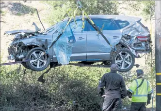  ?? RINGO H.W. CHIU / AP ?? A crane is used to lift a vehicle following a rollover accident involving golfer Tiger Woods, in the Rancho Palos Verdes suburb of Los Angeles on Feb. 23.