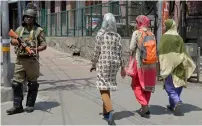  ?? AFP ?? Paramilita­ry trooper stands guard as Kashmiri girls walk past during a one-day strike in Srinagar Saturday. —