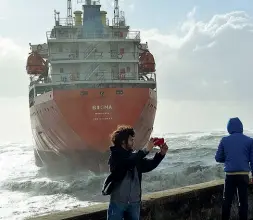 ??  ?? Uno dei tanti selfie scattati ieri davanti alla nave arenata: molti curiosi si sono fermati davanti alla «Sigma» per farsi una foto. Sotto, alcuni membri dell’equipaggio