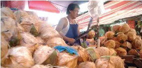  ??  ?? A VENDOR selling coconut at a local wet market.