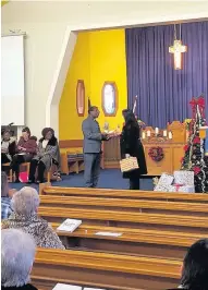  ??  ?? Christmas gift Reverend Ecilo Selemani hands the gifts to Townhead Primary head teacher Fiona Gamson