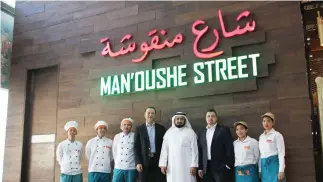  ??  ?? Khalid Abdullah Al-Rajhi poses with Jihad Al-Eit, CEO of Man’oushe Street, and his team during an event.