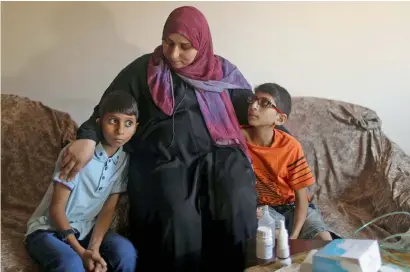  ?? Reuters ?? Palestinia­n boy Mohammed Shanty and his brother Mustafa, who suffer from cystic fibrosis, sit next to their mother after receiving oxygen therapy in Gaza City. —