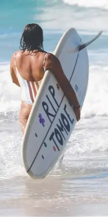  ?? Picture: LIANA TURNER ?? One of Tomoe Ogisu’s friends with a tribute on her board before the paddle-out at Fingal yesterday.