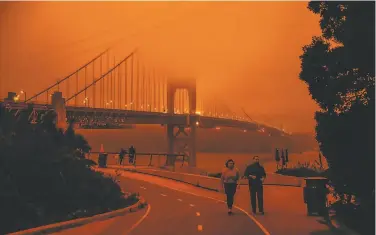  ?? Gabrielle Lurie / The Chronicle ?? The Golden Gate Bridge draws a few visitors Wednesday under a sky orange with wildfire smoke.