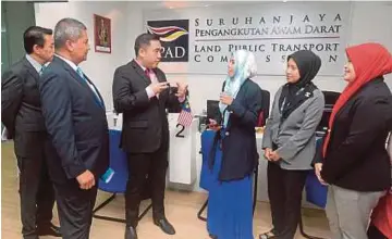  ?? PIC BY MOHD FADLI HAMZAH ?? Transport Minister Anthony Loke (third from left) talking to Land Public Transport Commission staff members at the commission’s counter in Putrajaya. With him is ministry secretary-general Datuk Seri Saripuddin
Kasim (second from left).