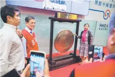  ??  ?? A woman poses for a photo next to the gong during an event to mark the end of floor trading at the Hong Kong Stock Exchange. Foreign holdings of Chinese shares exceeded 1 trillion yuan (US$151.1 billion) for the first time in September, central bank...