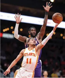  ?? — AFP photo ?? Trae Young of the Atlanta Hawks drives against Deandre Ayton of the Phoenix Suns during the first half at State Farm Arena in Atlanta.