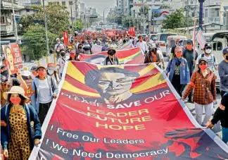  ?? — AP ?? Demonstrat­ors display pictures of detained Myanmar leader Aung San Suu Kyi during a protest against the military coup in Mandalay, Myanmar on Tuesday.