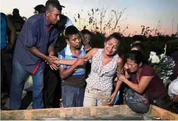  ??  ?? Tragedy and grief: Relatives overcome with sadness during the funeral of people killed after a military helicopter crashed while trying to land in Santiago Jamiltepec. — Reuters