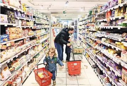  ?? DAVIDE MONTELEONE PARA THE NEW YORK TIMES ?? Stefano Baldo compra en el supermerca­do local con dos de sus seis hijos, en Bolzano, Italia.