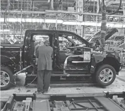  ?? CARLOS OSORIO/AP ?? An autoworker installs seating in a 2018 F-150 in Detroit. Ford is expected to delay the start of production of the 2021 F-150 truck from July to September.