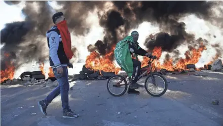  ?? MAJDI MOHAMMED/AP ?? Palestinia­n protesters pass burning tires during clashes with Israeli troops Friday near the West Bank city of Nablus.