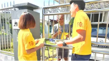  ??  ?? Representa­tives of SUPP Batu Kawah Service Centre give away pamphlets to a resident in Batu Kawah.